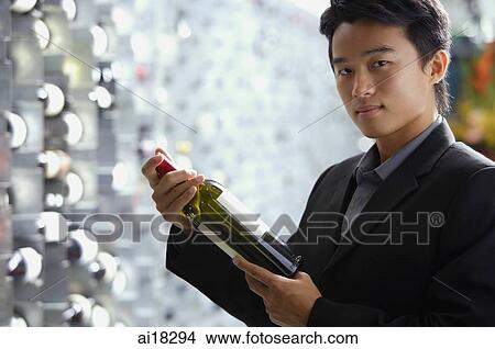 Man in wine cellar, holding bottle of wine View Large Photo Image Picture - Man in wine cellar, holding bottle of wine. Fotosearch