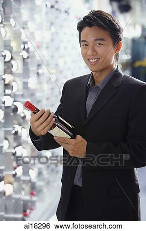 Man in wine cellar, holding bottle of wine, smiling at camera View Large Photo Image Stock Photograph - Man in wine cellar, holding bottle of wine, smiling at camera. Fotosearch