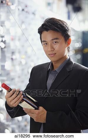 Man in wine cellar, holding bottle of wine, looking at camera View Large Photo Image Stock Photography - Man in wine cellar, holding bottle of wine, looking at camera. Fotosearch