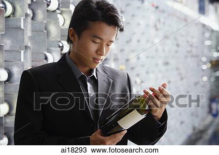 Man in wine cellar, looking at bottle of wine View Large Photo Image Stock Image - Man in wine cellar, looking at bottle of wine. Fotosearch