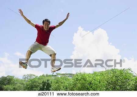 Stock Image - Man jumping in mid air, arms outstretched. Fotosearch