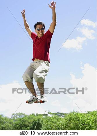 Man jumping in mid air, arms outstretched, smiling View Large Photo Image Stock Image - Man jumping in mid air, arms outstretched, smiling. Fotosearch