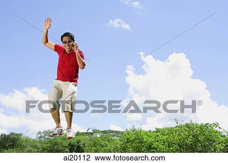Man jumping in mid air, holding mobile phone View Large Photo Image Stock Image - Man jumping in mid air, holding mobile phone. Fotosearch