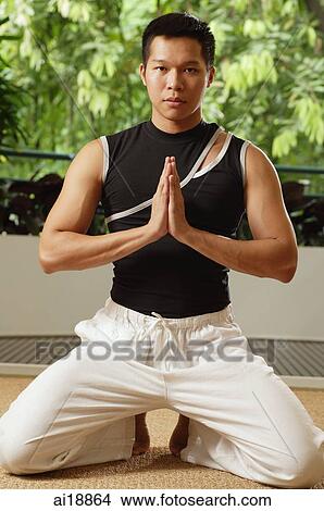 Picture - Man kneeling on floor, hands together. Fotosearch