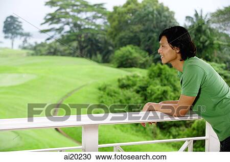 Man leaning on railing, looking out at golf course View Large Photo Image Stock Image - Man leaning on railing, looking out at golf course. Fotosearch