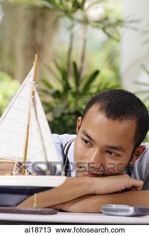Man looking a wooden model of boat, leaning on arms View Large Photo Image Stock Image - Man looking a wooden model of boat, leaning on arms. Fotosearch