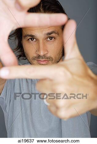 Man looking at camera through his fingers View Large Photo Image Stock Photo - Man looking at camera through his fingers. Fotosearch
