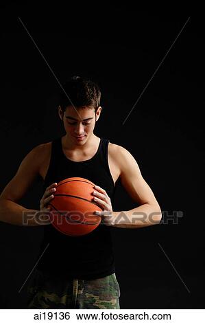 Stock Photograph - Man looking down at basketball in hands. Fotosearch