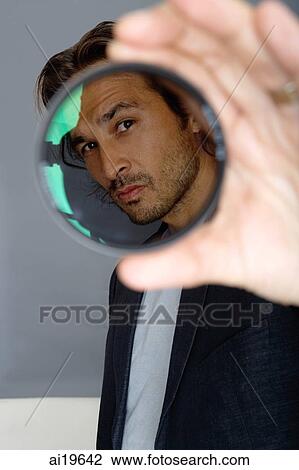 Stock Image - Man looking through lens. Fotosearch