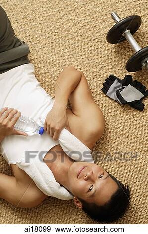 Man lying on mat, holding bottle of water, looking at camera View Large Photo Image Stock Photo - Man lying on mat, holding bottle of water, looking at camera. Fotosearch
