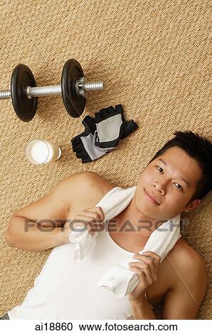 Man lying on matt, towel around his neck, looking at camera View Large Photo Image Stock Image - Man lying on matt, towel around his neck, looking at camera. Fotosearch