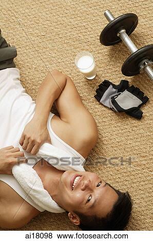Man lying on matt, towel around his neck, smiling at camera View Large Photo Image Stock Photo - Man lying on matt, towel around his neck, smiling at camera. Fotosearch