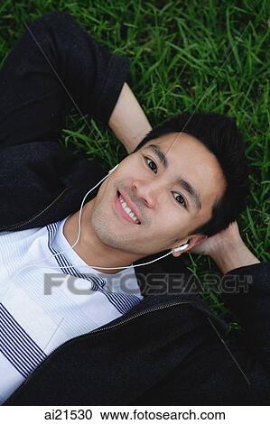 Man outdoors, listening to MP3 player, lying on grass View Large Photo Image Stock Image - Man outdoors, listening to MP3 player, lying on grass. Fotosearch