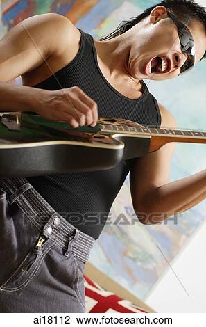 Stock Image - Man playing guitar, mouth open. Fotosearch