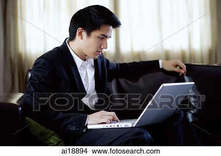 Man seating on sofa, using laptop, side view View Large Photo Image Picture - Man seating on sofa, using laptop, side view. Fotosearch