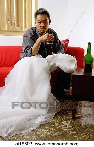 Man sitting at home, drinking, looking at wedding dress View Large Photo Image Stock Image - Man sitting at home, drinking, looking at wedding dress. Fotosearch