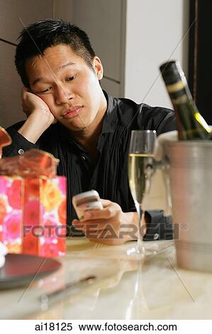 Man sitting at table, looking at mobile phone, leaning on hand View Large Photo Image Stock Photography - Man sitting at table, looking at mobile phone, leaning on hand. Fotosearch