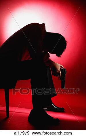 Man sitting in chair, bending forward, holding a gun View Large Photo Image Stock Photo - Man sitting in chair, bending forward, holding a gun. Fotosearch
