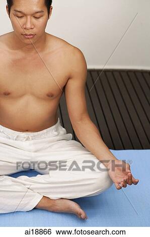 Stock Photograph - Man sitting in yoga position, meditating, high angle view. Fotosearch