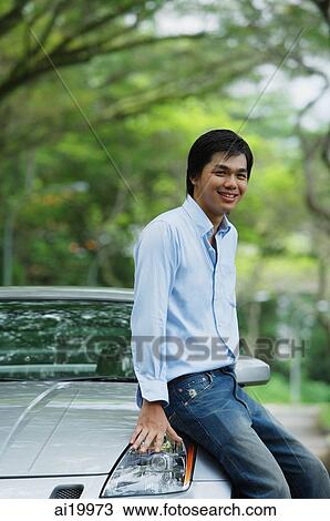 Man sitting on car hood, smiling View Large Photo Image Stock Image - Man sitting on car hood, smiling. Fotosearch