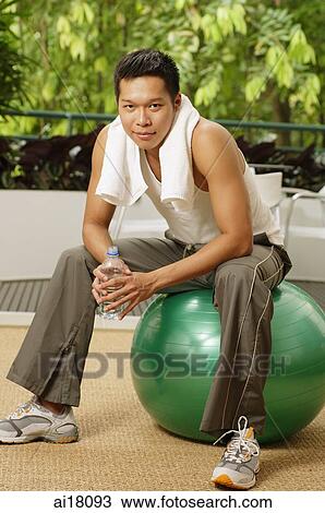 Man sitting on exercise ball, holding bottle of water, looking at camera View Large Photo Image Stock Image - Man sitting on exercise ball, holding bottle of water, looking at camera. Fotosearch