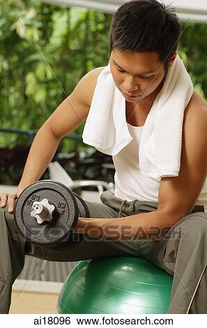 Man sitting on exercise ball, lifting dumbbells View Large Photo Image Stock Photograph - Man sitting on exercise ball, lifting dumbbells. Fotosearch