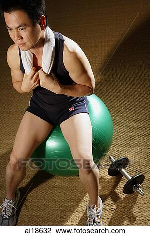 Man sitting on fitness ball, towel around neck, resting View Large Photo Image Stock Image - Man sitting on fitness ball, towel around neck, resting. Fotosearch