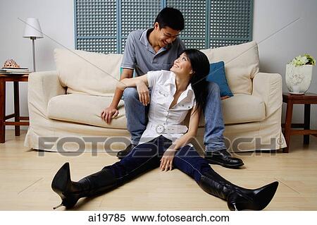 Man sitting on sofa, woman sitting on floor, looking at each other View Large Photo Image Stock Photography - Man sitting on sofa, woman sitting on floor, looking at each other. Fotosearch