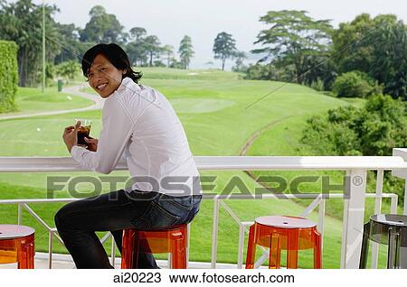 Man sitting on stool, looking over shoulder at camera View Large Photo Image Stock Image - Man sitting on stool, looking over shoulder at camera. Fotosearch