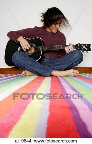 Man sitting on striped carpet, playing with guitar View Large Photo Image Picture - Man sitting on striped carpet, playing with guitar. Fotosearch