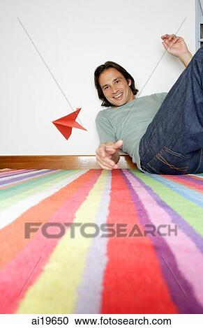Man sitting on striped carpet, throwing paper airplane View Large Photo Image Stock Image - Man sitting on striped carpet, throwing paper airplane. Fotosearch