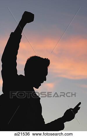 Stock Photograph - Man standing in silhouette, arm raised in victory. Fotosearch