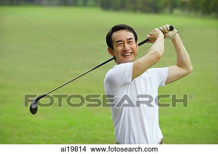 Picture - Man swinging golf club, smiling at camera. Fotosearch