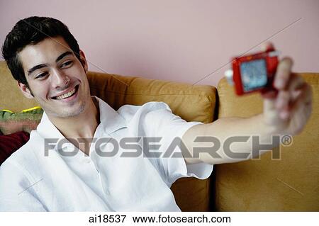 Stock Photo - Man using camera to take photo of himself. Fotosearch