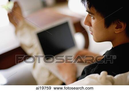 Stock Photo - Man using laptop, over the shoulder view. Fotosearch