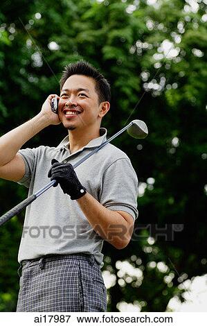 Stock Photo - Man with golf club on shoulder, using mobile phone. Fotosearch