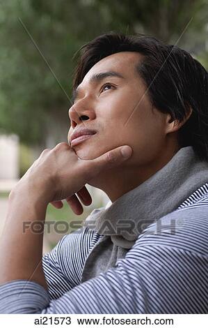 Stock Image - Man with hand on chin, looking up. Fotosearch