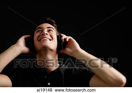 Stock Photo - Man with headphones, listening to music, looking up. Fotosearch