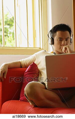 Man with headphones, looking at laptop View Large Photo Image Stock Photo - Man with headphones, looking at laptop. Fotosearch