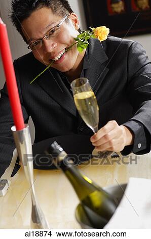 Man with rose stalk between teeth, holding champagne glass, smiling View Large Photo Image Picture - Man with rose stalk between teeth, holding champagne glass, smiling. Fotosearch