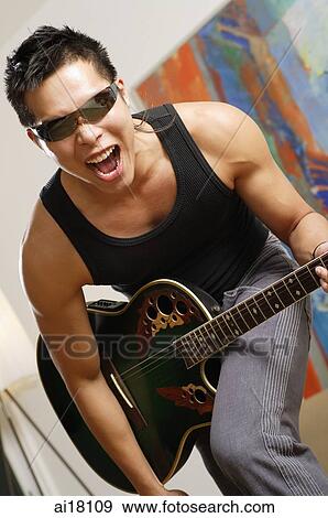 Stock Photo - Man with sunglasses and guitar, mouth open. Fotosearch