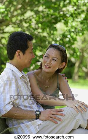 Mature couple sitting on bench, looking at each other View Large Photo Image Stock Photograph - Mature couple sitting on bench, looking at each other. Fotosearch