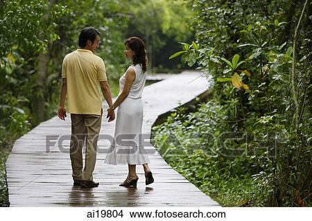 Mature couple walking along path in park, holding hands View Large Photo Image Picture - Mature couple walking along path in park, holding hands. Fotosearch