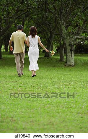 Mature couple walking in park, holding hands, rear view View Large Photo Image Stock Image - Mature couple walking in park, holding hands, rear view. Fotosearch