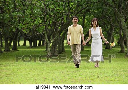 Mature couple walking in park, holding hands, smiling View Large Photo Image Stock Image - Mature couple walking in park, holding hands, smiling. Fotosearch