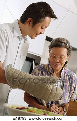 Stock Image - Mature son and mother in the kitchen. Fotosearch