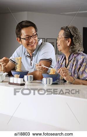Mature son and mother sitting at kitchen counter having noodles View Large Photo Image Stock Image - Mature son and mother sitting at kitchen counter having noodles. Fotosearch