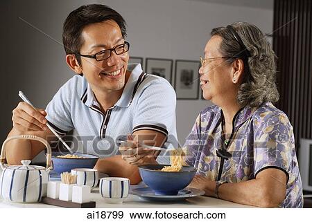 Mature son and mother sitting at kitchen counter with bowls of noodles View Large Photo Image Stock Photo - Mature son and mother sitting at kitchen counter with bowls of noodles. Fotosearch