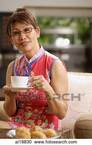 Mature woman at home, holding cup and saucer View Large Photo Image Stock Image - Mature woman at home, holding cup and saucer. Fotosearch