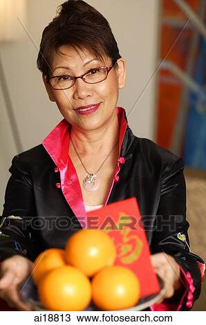 Mature woman holding basket of oranges View Large Photo Image Stock Image - Mature woman holding basket of oranges. Fotosearch